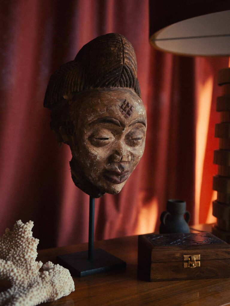 Picobello (2026) – Behind the Scenes Still - production design Picobello (2026) – Production Design for short film, surreal still life with sculptural mask on stand before red curtain, warm sunlight, Twin Peaks–like mood
