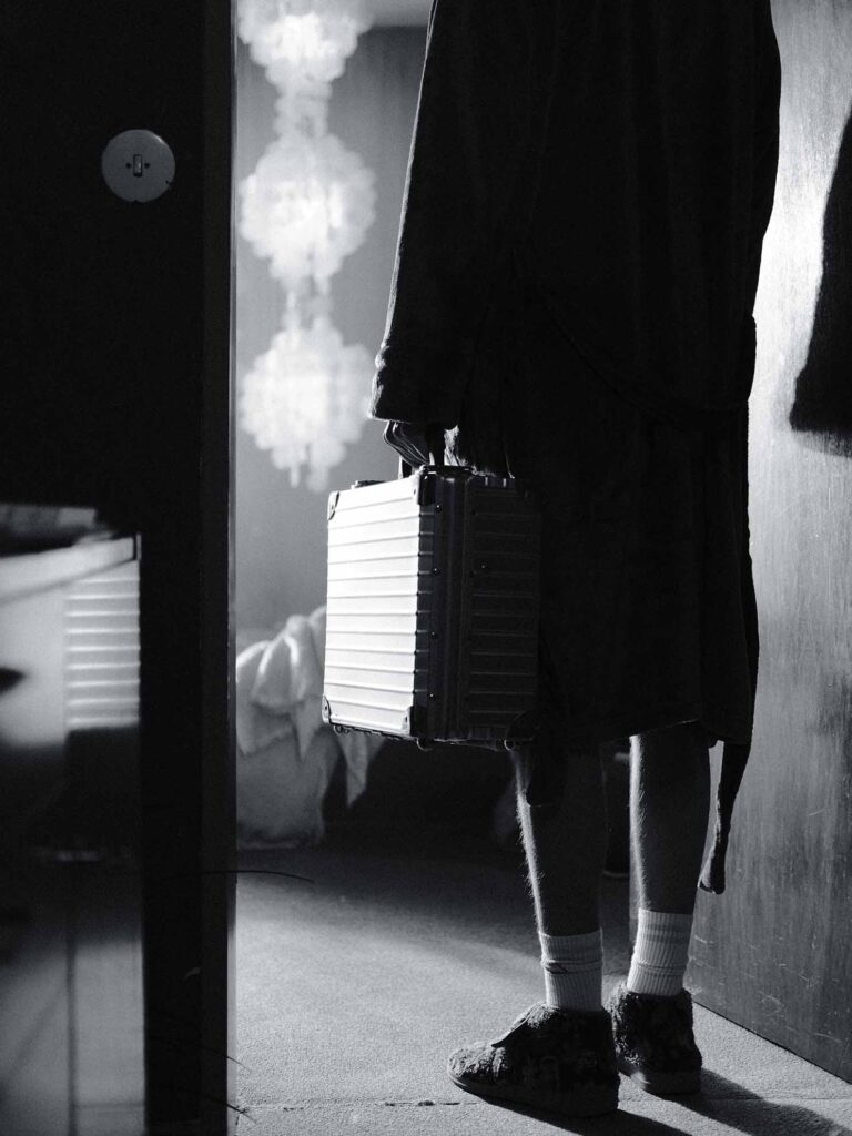 Picobello (2022) – Behind the Scenes Still - production design Picobello (2022) – Production Design for short film, silhouetted figure with briefcase in doorway, high-contrast light, noir mood, sparse interior
