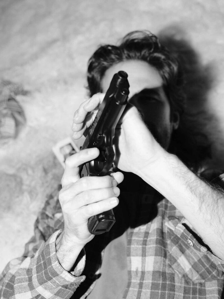 Picobello (2022) – Behind the Scenes Still - production design Picobello (2022) – Production Design for short film, black-and-white close-up of director holding prop handgun, dramatic light and shadow on face