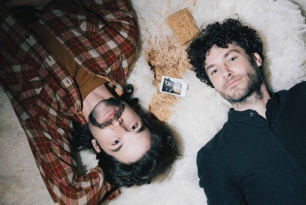 Picobello (2022) – Production Design for short film, two directors lie on rug beside sponge and small photo, relaxed behind-the-scenes setup